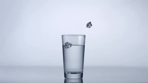 Slo-motion ice cubes falling into glass