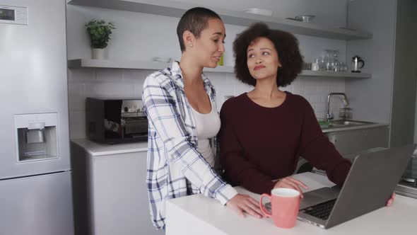 Lesbian couple using laptop in kitchen