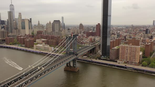 An aerial view over the East River on a cloudy day. The camera descends and pan left near the north