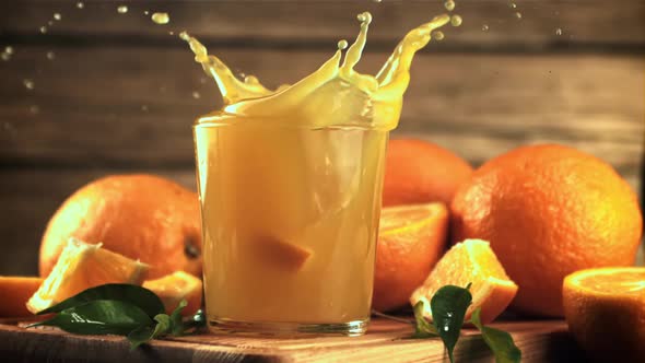 A Piece of Orange Falls Into a Glass of Juice with Splashes