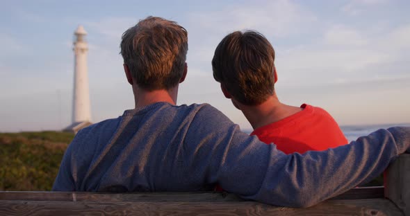 Couple embracing by the sea near a lighthouse