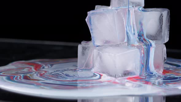 Multicolored Paint Spreads Over the Surface of the Ice Cubes and Flows Down Onto the Plane