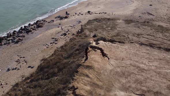 Beautiful aerial view of a drone, a happy woman dancing on the edge of a cliff with an ocean view.