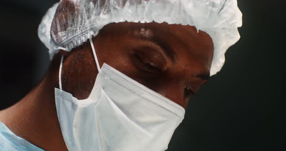 Closeup of a Doctor's Face in a Medical Mask and a Disposable Cap on His Head