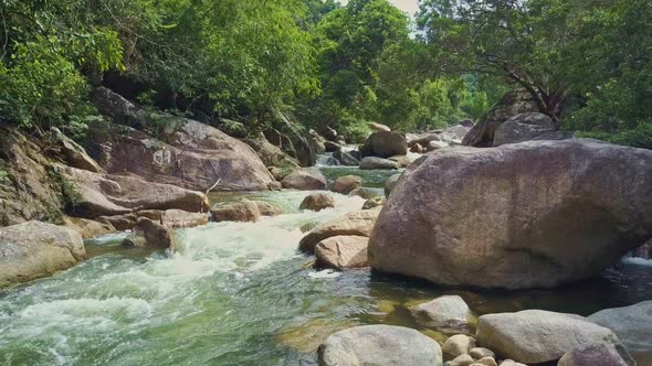 Flycam Shows Foamy River Swirling Between Large Boulders