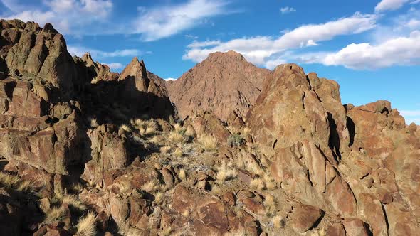 Flying through gap on rocky mountain top viewing desert valley