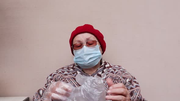 The Elderly woman in the medical mask wearing the gloves to protect herself from coronavirus.