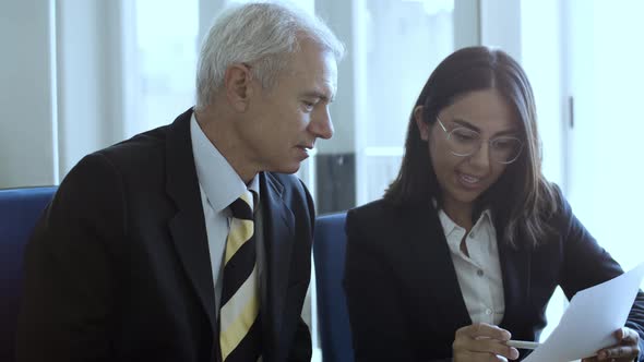 Female Professional in Suit and Glasses Explaining Document