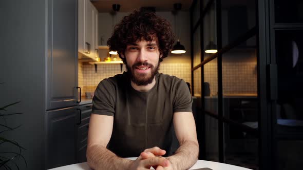 POV of Cheerful Young Man Chatting on Webcam with Friend on Laptop at Modern Kitchen