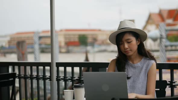 Young Asian woman using laptop working at a cafe shop.