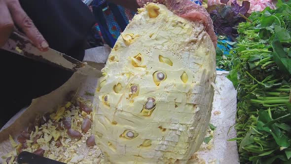 HIKKADUWA, SRI LANKA - MARCH 2014: Woman cutting durian fruit with big knife at Sunday market