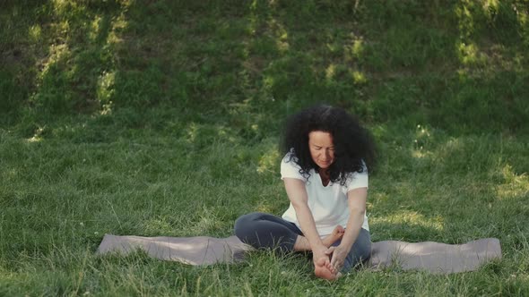 Middle Aged Woman Doing Morning Yoga Outdoors in a Park