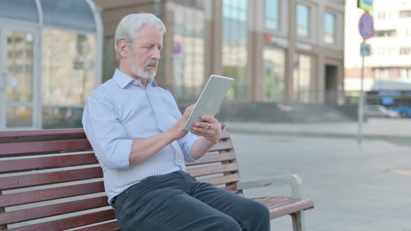 Old Man Using Tablet While Sitting Outdoor on Bench