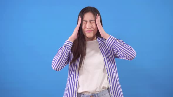 Young Asian Woman Has a Headache on a Blue Background