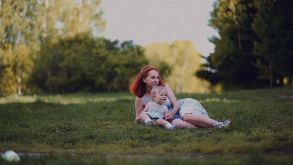 mother and baby sit in a park or in a forest