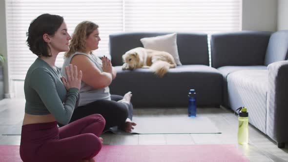 Caucasian lesbian couple keeping fit and meditating on yoga mat