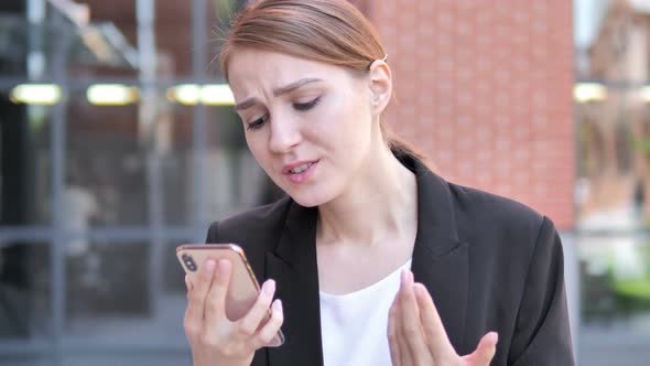 Outdoor Young Businesswoman Upset by Loss while Using Smartphone