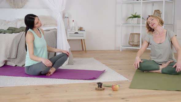 Professional Yoga Instructor and Young Lady Stretching Neck