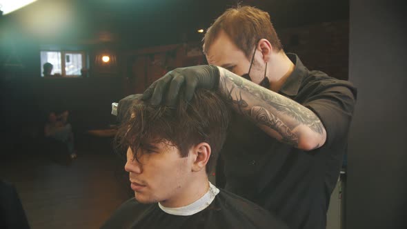 Tattooed Barber Cutting Out the Hair Edging on the Client with a Hair Trimmer