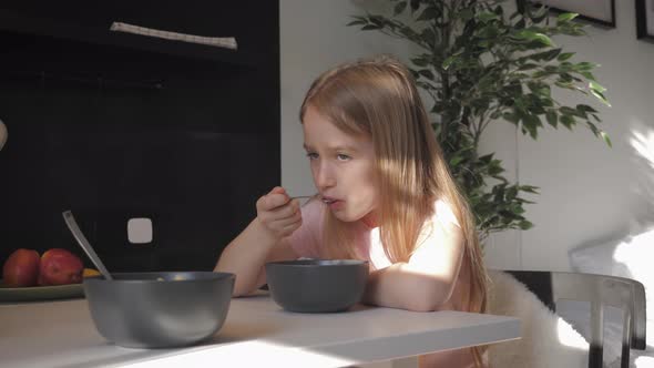 Cute Teenage Girl Sits at the Dinner Table and Eating Porridge for Breakfast. Healthy Lifestyle