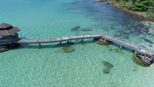 Drone shot of wooden footbridge leading into the sea. Koh Kood, Thailand. PAN RIGHT TO LEFT