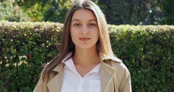 Portrait of Young Attractive Female Who Smiling and Looking at the Camera on Green Historical Urban