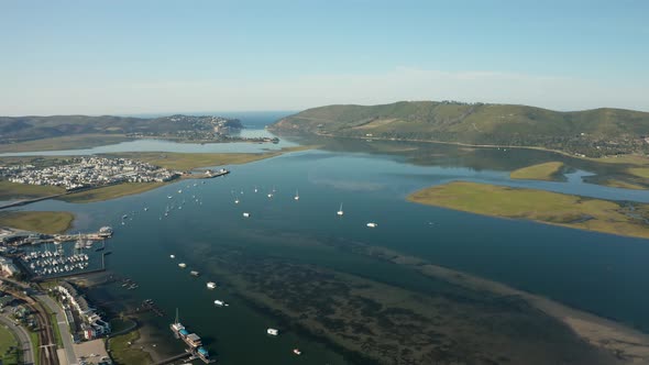 Aerial tilt up of Knysna river mouth and sailing boats in the harbor