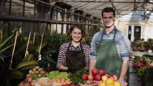 Portrait of Beautiful Caucasian Farmers  Man and Woman in Aprons Selling Organic Food in Farm Market