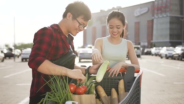 Young Asian Man and Woman Looking at the Products which they Bought in the Supermarket