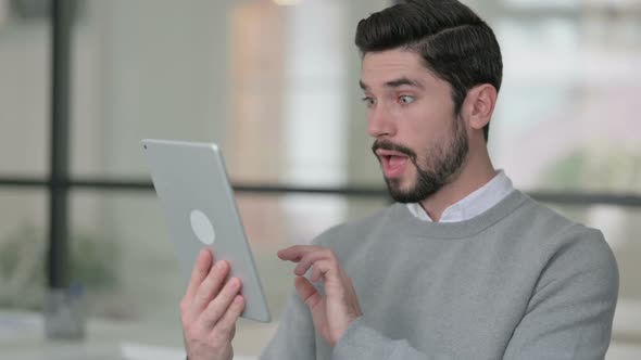 Portrait of Young Man Celebrating on Tablet in Office