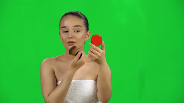 Makeup. Woman Applying Powder on Face Skin Looking in a Red Mirror