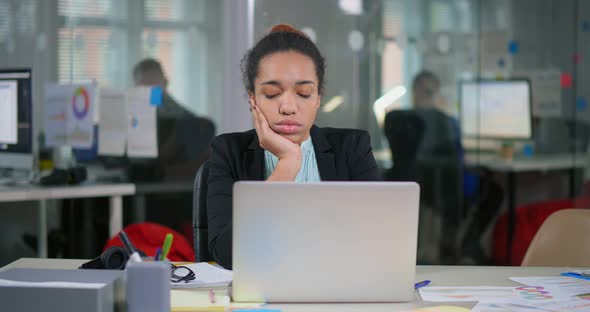 African Bored Woman Sitting in Office in Front of Laptop