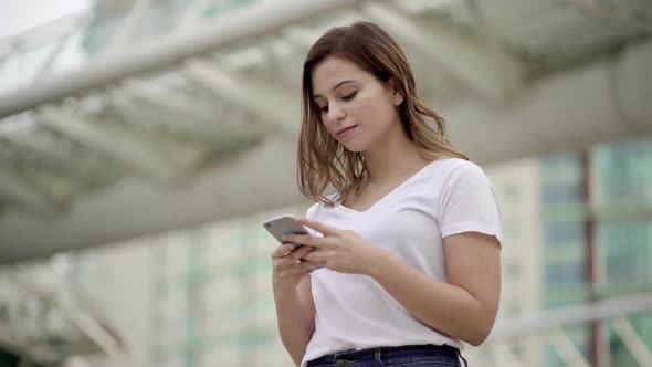 Beautiful Young Woman Walking on Street with Phone