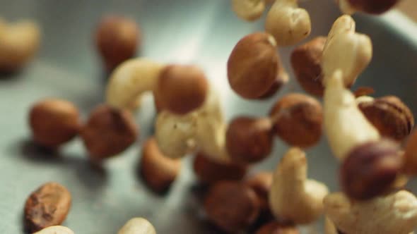 Closeup Nuts Frying on Metal Pan in Slow Motion. Mix of Hazel and Cashew Nuts