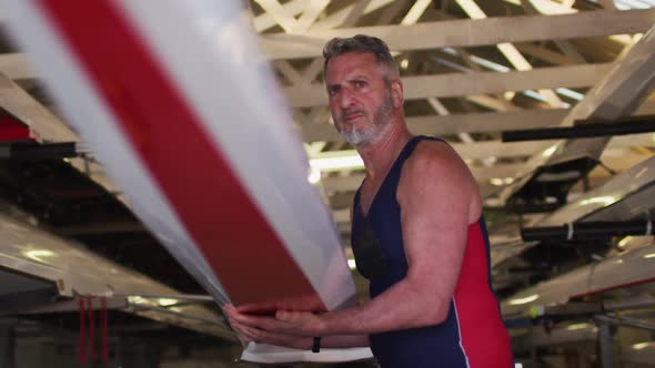 Senior caucasian man carrying a rowing boat