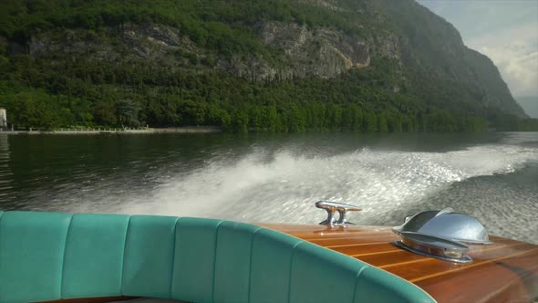 Water spray comes from a classic luxury wooden runabout boat on an Italian lake.