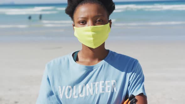 Portrait of african american woman wearing volunteer t shirt and face mask looking at camera