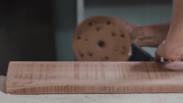 Man Worker Makes the Side of a Wooden Detail Softer Using a Grinding Machine