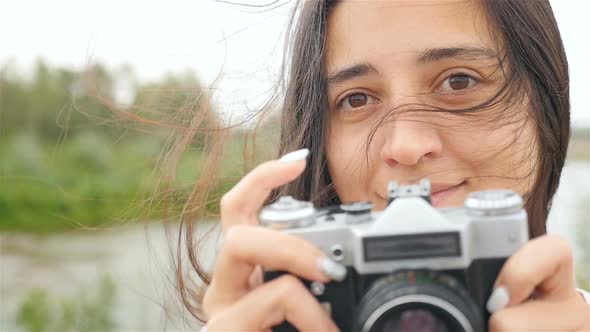 A Beautiful Girl Holds a Camera and Takes Pictures