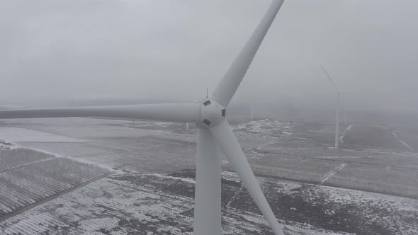 Wind turbine in a snowy landscape with early winter morning mist.