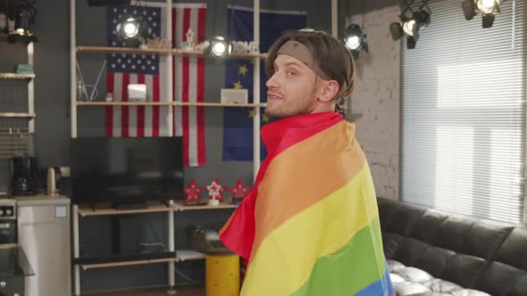 Gay Man with Rainbow Flag Posing at Home