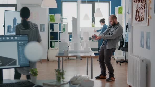 Architect Using Mobile Phone to Create Blueprints Plan with Building Model and Maquette