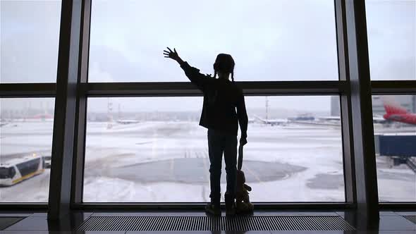 Little Girl in Airport Near Big Window While Wait for Boarding