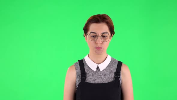 Portrait of Funny Girl in Round Glasses Is Waiting and Angry. Green Screen