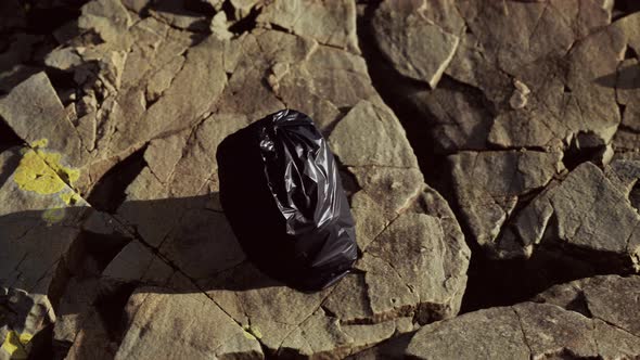 Black Trash Bag Lay on a Rocky Beach