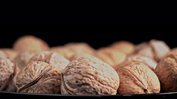 Lot of Walnuts in the Shell are Spinning on a Black Background