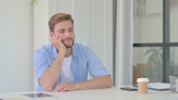 Young Creative Man Taking Nap While Sitting in Office