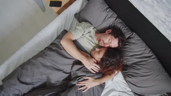Man Hugging and Kissing Wife while Sleeping on Bed