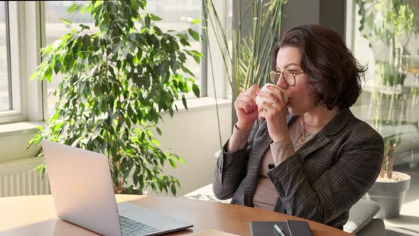 Young business woman having coffee break at work on laptop computer in office. 