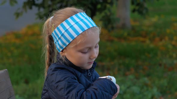 Child using smartwatch outdoor in autumn park. Kid talking on vdeo call on smartphone outdoor